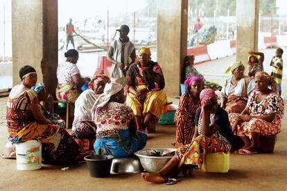 Un grupo de mujeres ghanesas espera en el puerto la llegada de los marineros para poder comprar el pescado. Sale el sol y el enclave de San Pedro, al suroeste de Costa de Marfil, da fe de su fama. La actividad es incesante en el muelle ya que desde aquí sale para el extranjero el producto estrella de Costa de Marfil: el cacao.