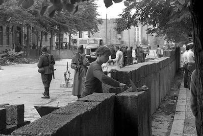 Agosto de 1961: Un obrero trabaja en la construcción del Muro bajo vigilancia militar