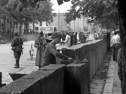 Agosto de 1961: Un obrero trabaja en la construcción del Muro bajo vigilancia militar