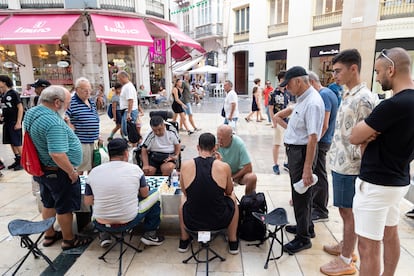 Varias personas juegan al ajedrez en la calle Larios, en Málaga.