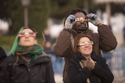 Varias personas miran un eclipse junto al Planetario de Madrid, que reparte gafas especiales en esas observaciones públicas.