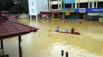 Vecinos de Kuala Krai (norte del país) emplean un bote para inspeccionar la zona.