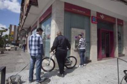 Unas personas esperan en el cajero de una sucursal de Cajasur en Córdoba. EFE/Archivo