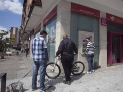 Unas personas esperan en el cajero de una sucursal de Cajasur en Córdoba. EFE/Archivo