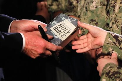Un integrante de la Marina de los Estados Unidos le entrega su Biblia al presidente de Estados Unidos para que la autografíe mientras el mandatario saluda a los marineros después de su discurso a bordo de la USS Wasp en JMSDF.