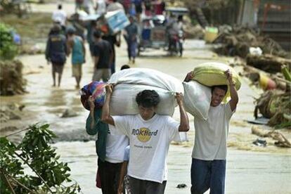 Varios afectados por las inundaciones evacuan sus casas con sus pertenencias, ayer a 70 kilómetros de Manila.
