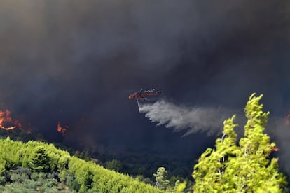 Un helicóptero arroja agua sobre una montaña durante un incendio forestal en la aldea de Platanos, cerca de la antigua Olimpia, en el oeste de Grecia.