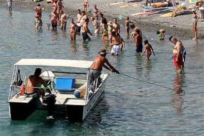 Un operario recoge medusas frente a la playa de Salobreña (Granada) el pasado lunes.