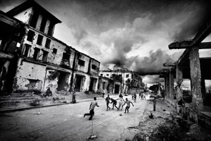 Un grupo de niños juega al fútbol en una calle de Mogadiscio entre edificios en ruinas por los enfrentamientos armados.  Esta fotografía forma parte de <i>Somalia en el fin del mundo</i>, reportaje fotográfico galardonado con el Premio Ortega y Gasset de Fotografía 2009, publicado en el <i>Magazine</i> de <i>La Vanguardia</i> del 1 de febrero de 2009.