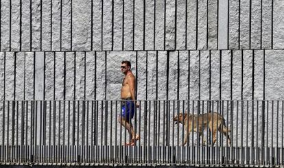 Un hombre pasea con su perro por Madrid Rio durante la ola de calor.