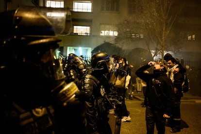 A protester uses eye drops to ease the effects of teargas as he faces off with riot police during a demonstration a few days after the government pushed a pensions reform through parliament without a vote, using the article 49,3 of the constitution in Lyon, eastern France on March 20, 2023. 