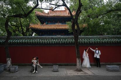 A bride and groom pose for a photo outside the Temple of Confucius, in Beijing, on September 26, 2023.