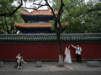 A bride and groom pose for a photo outside the Temple of Confucius, in Beijing, on September 26, 2023.