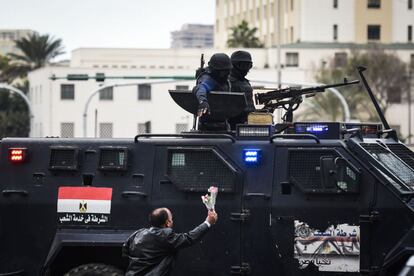 Un hombre egipcio ofrece flores a la policía de fuerzas especiales que patrullan en la Plaza de Tahrir de el Cairo.