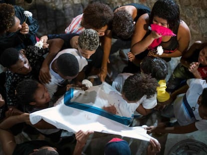 Amigos e familiares de Marcos Vinícios choram sobre sua camiseta da escola manchada de sangue, durante o seu velório.