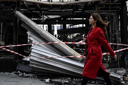 Una mujer pasa junto a los restos de un puesto de periódicos en París (Francia) dos días después de que fue dañada por los manifestantes durante los enfrentamientos con las fuerzas de la policía antidisturbios en los Campos Elíseos durante el decimoctavo sábado consecutivo de manifestaciones convocadas por el movimiento de los chalecos amarillos.