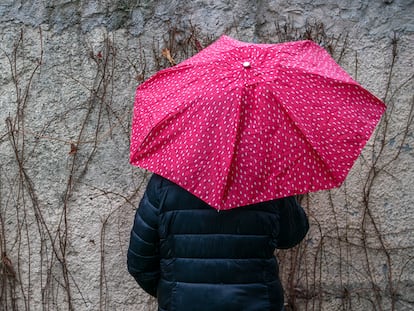 Sandra (nombre figurado) esconde su rostro tras un paraguas un día de lluvia en un municipio de la Comunidad de Madrid.
