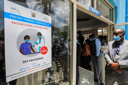 Un oficial de seguridad vigila, junto a un cartel pegado en la entrada que anuncia que las vacunas de covid-19 están disponibles de forma gratuita, durante el lanzamiento oficial de la campaña de vacunación de los sanitarios del Hospital Nacional Kenyatta (KNH), en Nairobi, Kenia, el 5 de marzo de 2021.