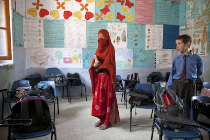 Un colegio de Machulu con murales, mapas y gráficos del cuerpo humano en las paredes de las aulas. Mochilas sobre las sillas. Igual que en cualquier parte del mundo. Un alumno uniformado mira a la maestra. El uniforme lo mantienen por tradición británica (Pakistán fue colonia de Reino Unido). La Fundación Baltistan ha conseguido que algunas de sus alumnas se formen como profesoras para que puedan continuar la labor educacional iniciada. Esta mujer solo deja ver sus ojos. Se tapa porque va a ser fotografiada. En época de cosecha, los maestros tienen que negociar con las familias que obligan a sus hijas a ayudar en el campo, ya que la agricultura también es tarea de mujeres.