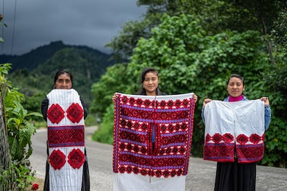 Las artesanas, Antonia Sántiz López, Sofía Luna Sántiz y Petrona Girón Méndez posan para una fotografía con bordados elaborados por ella en Tenejapa, Chiapas, el 30 de junio de 2021.