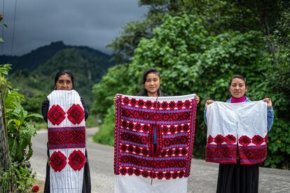 Las artesanas, Antonia Sántiz López, Sofía Luna Sántiz y Petrona Girón Méndez posan para una fotografía con bordados elaborados por ella en Tenejapa, Chiapas, el 30 de junio de 2021.