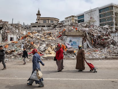 Varias mujeres caminan con bolsas de la compra delante de edificios derrumbados en Kahramanmaras (Turquía), tras un fuerte terremoto el 22 de marzo.