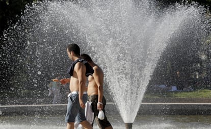 Dos hombres caminan, ayer, junto a la fuente del Templo de Debod en Madrid.