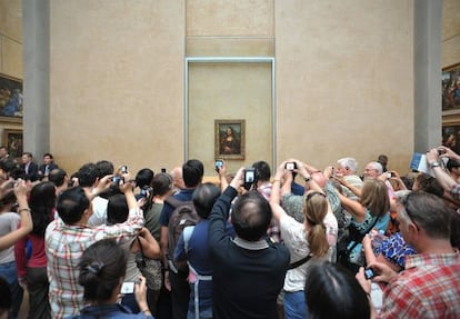 Desenes de turistes fotografien la Monna Lisa al Louvre.