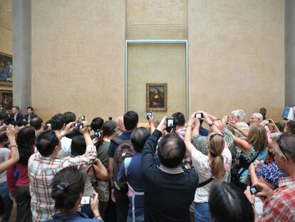 Desenes de turistes fotografien la Monna Lisa al Louvre.