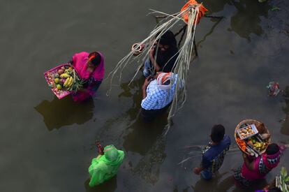 Indian Hindu devotees perform religious rituals as they offer prayers to the sun god on the banks of the Yamuna river during the Chhath Festival in Allahabad on October 26, 2017. 
The Chhath Festival, also known as Surya Pooja, or worship of the sun, is observed in parts of India and Nepal and sees devotees pay homage to the sun and water gods. Devotees undergo a fast and offer water and milk to the sun god at dawn and dusk on the banks of rivers or small ponds and pray for the longivety and health of their spouse. / AFP PHOTO / SANJAY KANOJIA