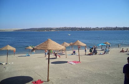 Sombrillas y cemento en la orilla de la playa Costa Dulce, en Orellana la Vieja (Badajoz).