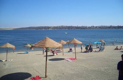 Sombrillas y cemento en la orilla de la playa Costa Dulce, en Orellana la Vieja (Badajoz).