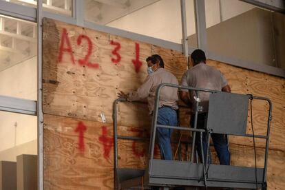 Trabajadores colocan tablas de madera en las ventanas de un supermercado para evitar los daños que pueda provocar 'Grace'. Las autoridades alertan a la población para que se prepare en caso de una posible evacuación, por lo que se han activado 217 inmuebles que funcionarán como refugios temporales en el Estado.