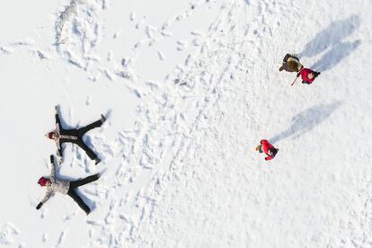 Niños juegan en la nieve mientras la gente camina al lado del lago helado 'Lac de Joux' en Le Pont (Suiza), el 4 de marzo de 2018.