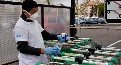 Un empleado de limpieza desinfecta los carros de la compra de Mercadona en Calafell.