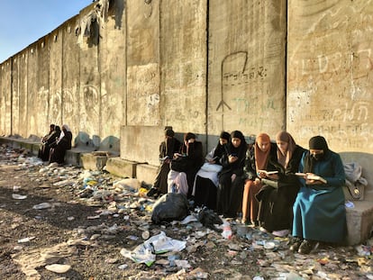 Unas mujeres palestinas leen el Corán ante uno de los accesos cerrados al puesto de Qalandia, este viernes.