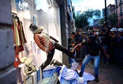 Manifestantes enmascarados vandalizan una tienda en Ciudad de México, el 2 de octubre de 2018, durante la manifestación. 