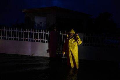 Según datos oficiales, Fiona ha dejado a más de 1.4 millones de puertorriqueños sin luz. En la imagen, un hombre enfundado en un traje impermeable se para junto a una vivienda en medio de la oscuridad, en el municipio de Guayanilla, la noche del 18 de septiembre de 2022.  