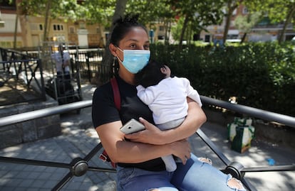 A woman wearing a face mask holds her baby on May 25.