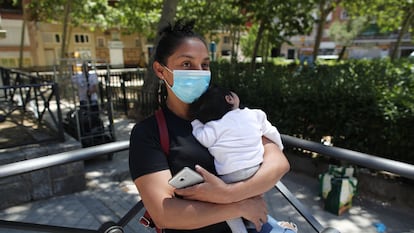 A woman wearing a face mask holds her baby on May 25.