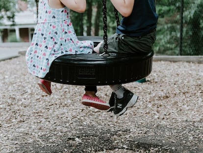 Dos niños suben a un columpio. 