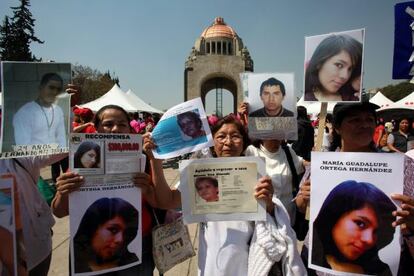 Mujeres muestran fotos de desaparecidos en México.