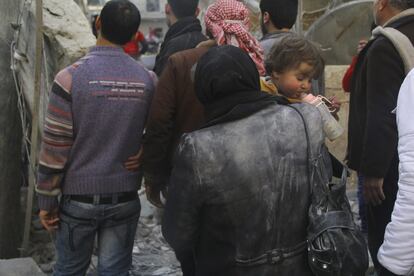 Una madre con su hija en brazos salen de la zona afectada por los bombardeos en la ciudad de Alepo (Siria), 31 de enero de 2014.