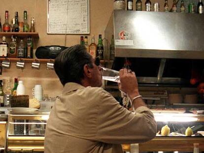 Un hombre bebe en la barra de un bar.