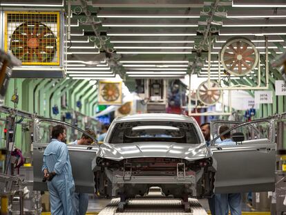 Varios trabajadores de la planta de pintura de Ford en Almussafes revisan una carrocería.