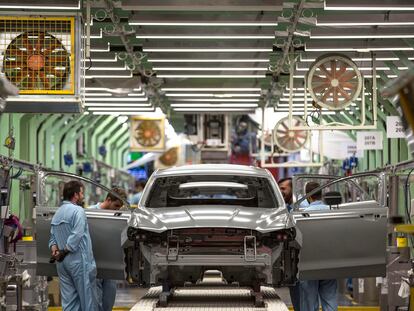 Varios trabajadores de la planta de pintura de Ford en Almussafes revisan una carrocería.