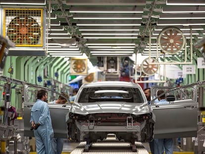 Varios trabajadores de la planta de pintura de Ford en Almussafes revisan una carrocería.