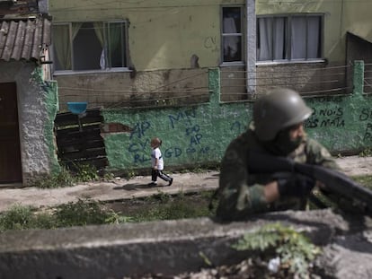 Uma menina passa por um soldado armado, durante uma operação surpresa na Cidade de Deus, no Rio de Janeiro.