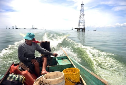 Un pescador navega frente a una torre petrolera en el lago Maracaibo.