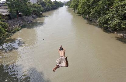 Un hombre salta a las aguas del río Tolly Nullah un día caluroso en Calcuta (India).